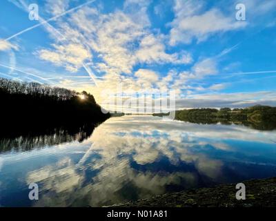 UK Weather: Sunny morning at Rivington. Cold sunny winter morning with sun and clouds reflected in Rivington reservoir near Chorley in Lancashire Stock Photo