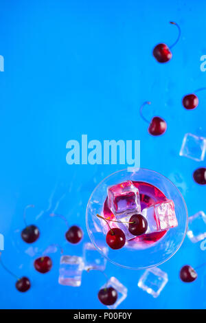 Cherry cider cocktail glasses from above on a blue background. Refreshing cold drink flat lay with copy space Stock Photo