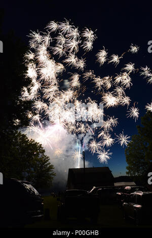 Colorful fireworks light up the night sky over a small town. Stock Photo