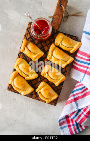 Top view of chilean empanadas on a wooden plate with ketchup. White stone background. Stock Photo