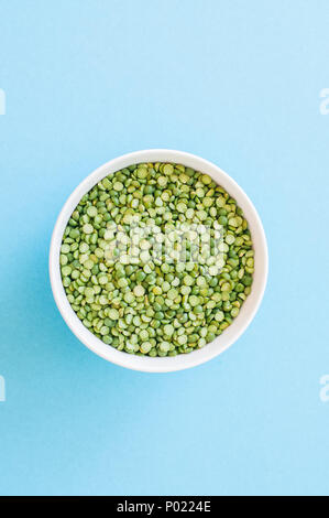 Dry uncooked green peas in a white bowl on a light blue background. Top view and copy space. Stock Photo