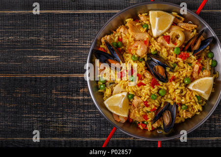 Paella with chicken,  seafood, vegetables and saffron served in the traditional pan, top view. Stock Photo