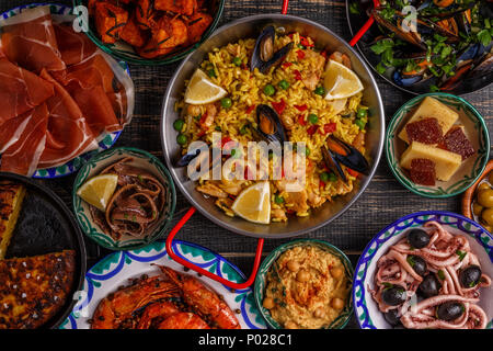 Typical spanish tapas concept. Concept include slices jamon, bowls with olives,  anchovies, spicy potatoes, mashed chickpeas, shrimp, calamari, manche Stock Photo