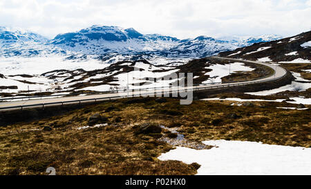 Back lit view over mountain landscape. Melting snow and ice in the terrain. Location along road E134 by the lake Kjelavatn in Telemark, Norway. Stock Photo