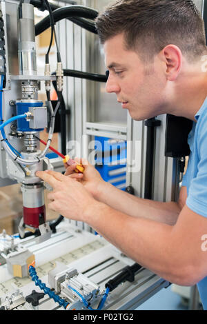 Male Engineer Working On Machine In Factory Stock Photo