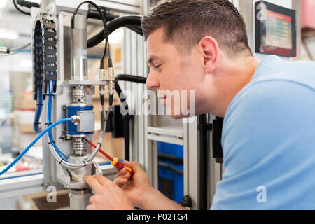 Male Engineer Working On Machine In Factory Stock Photo