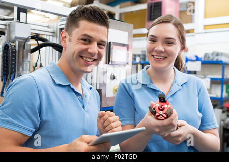Portrait Of Engineer And Apprentice Examining Component In Factory Stock Photo