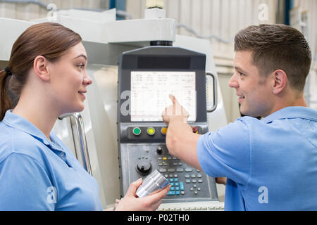 Engineer Instructing Female Apprentice On Use Of CNC Machine Stock Photo