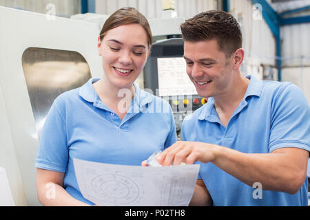 Engineer Instructing Female Apprentice On Use Of CNC Machine Stock Photo