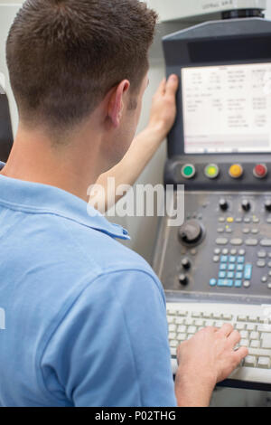 Rear View Of Male Engineer Operating CNC Machine In Factory Stock Photo