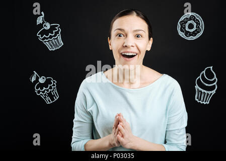 Excited middle aged woman feeling impressed while looking at the cakes Stock Photo