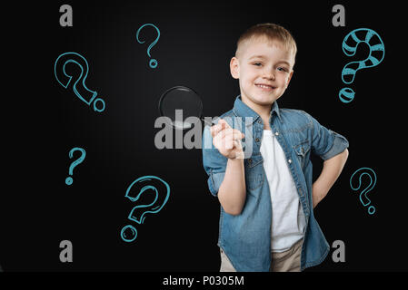 Cute boy holding a magnifying glass and looking glad Stock Photo