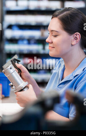Female Apprentice Measuring Component In Factory Stock Photo