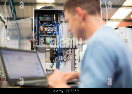 Male Engineer In Factory Using Laptop Computer Stock Photo