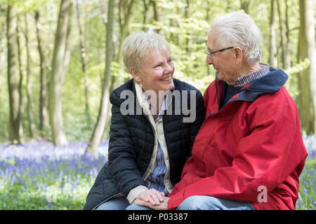 Loving Senior Couple Taking Break On Walk Through Bluebell Wood Stock Photo