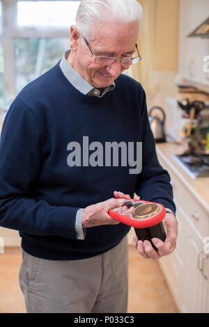 Senior Man In Kitchen Taking Lid Off Jar With Kitchen Aid Stock Photo