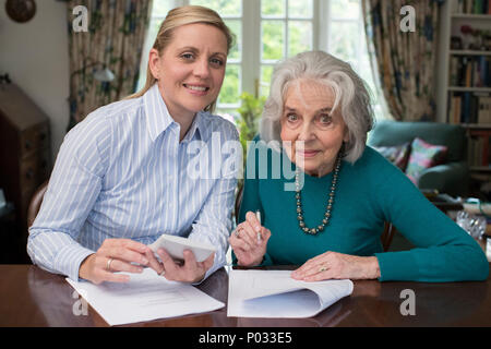 Portrait Of Woman Helping Senior Neighbor With Paperwork Stock Photo
