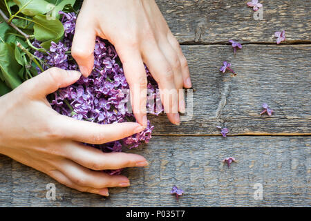 Women's hands folded in the form of a heart on the colors of lilac.Wooden background. Stock Photo