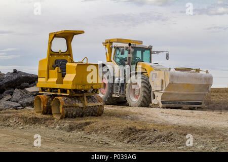 yellow loader and small road roller at a loamy construction site Stock Photo