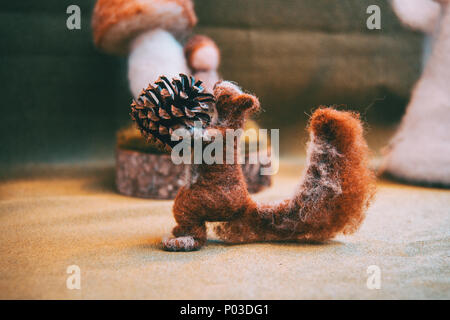 Felt brown squirrel holding a pine cone Stock Photo
