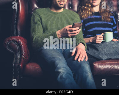 A young man on a sofa is showing his girlfriend something on his phone Stock Photo