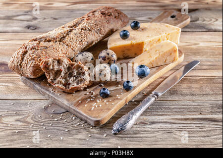 Baguette, cheese with spices and herbs, quail eggs, blueberries. Tasty and healthy bio food concept Stock Photo