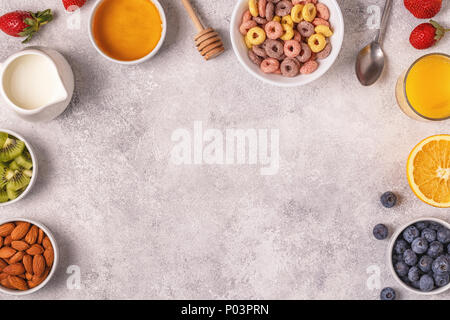 Breakfast with colorful cereal rings, fruit, milk, juice. Top view. Stock Photo
