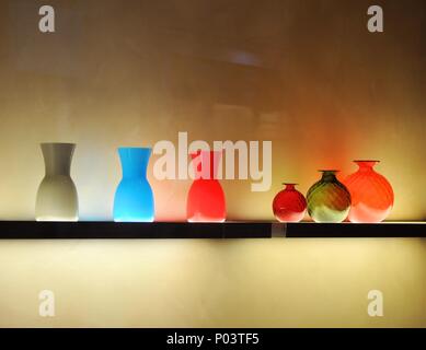 Multicolored glass jars in a row on the wall plastered Stock Photo