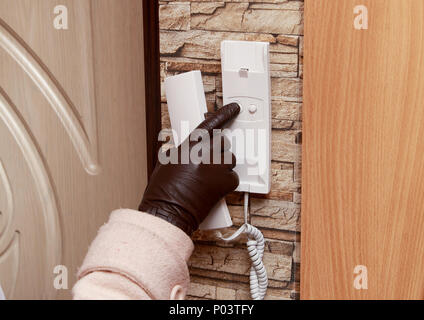 Close-up of the female hand in the glove presses the intercom button. Stock Photo