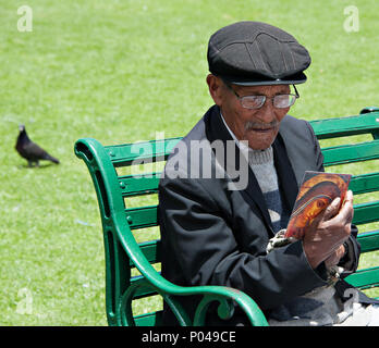 An old man sitting on a park bench in Cusco Peru South America Stock Photo