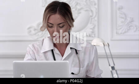 Serious female doctor using her laptop computer in medical office Stock Photo