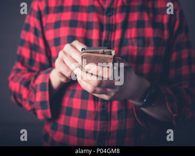 Close up on the hands of a young man using a smart phone Stock Photo