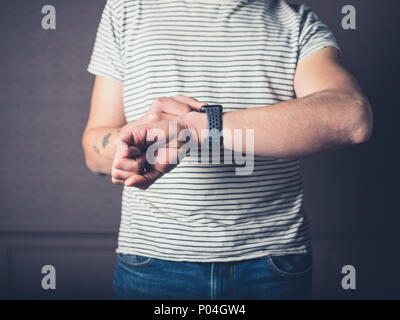 A young man is using his smart watch in a luxury living room Stock Photo