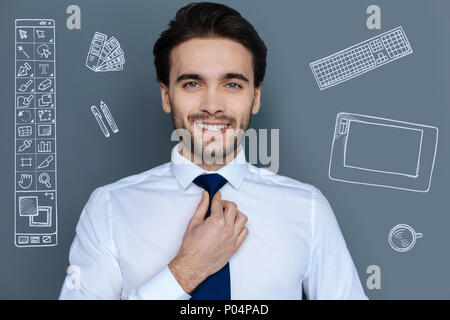 Elegant designer looking confident and touching his tie Stock Photo