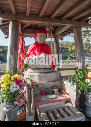 Roadside shrine, henro no michi pilgrim trail, Jizo Bosatsu statue in red robes, with offerings, Kochi, Shikoku, Japan Stock Photo