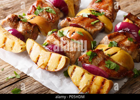 Spicy pork kebabs with apples and red onions close-up on the table. horizontal, rustic Stock Photo