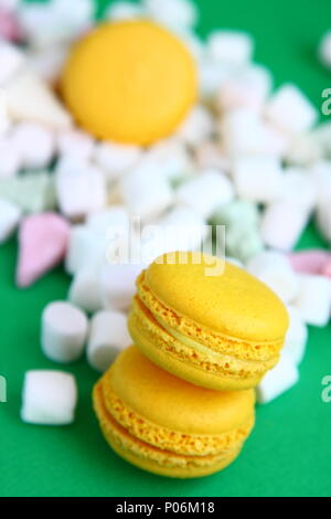Yellow macaroons and marshmallow on green Stock Photo