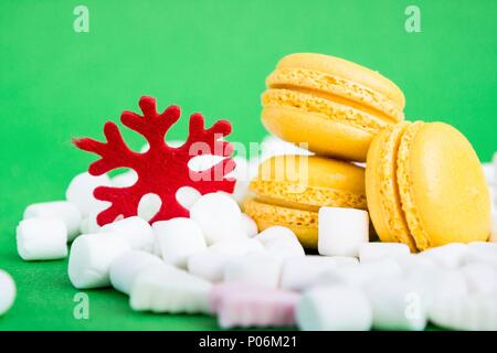 Yellow macaroons, marshmallow and red flake on green Stock Photo