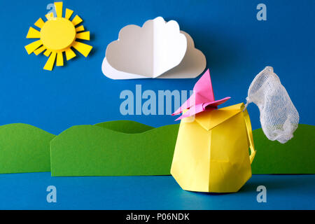 Paper backpack with butterfly net on grass field at blue background. Summer adventure. Camping and hiking or tourism concept. Origami. Paper cut. Stock Photo