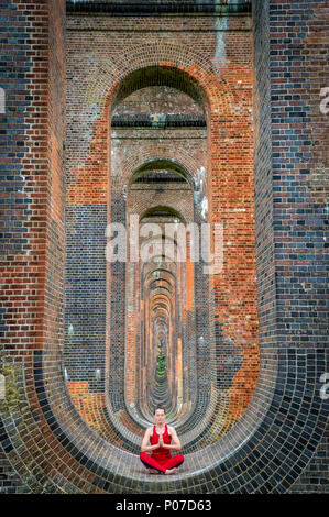 woman sitting in the arches of the Ouse Valley Viaduct practicing yoga and meditating