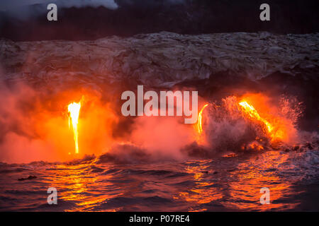 Hot molten lava flowing into the ocean on the Big Island of Hawaii during an active lava flow and volcanic eruption during sunrise. Stock Photo