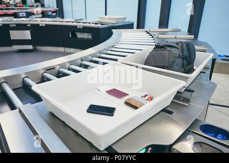 Airport security check. Containers with personal belongings (passport, smart phone, wallet, keys) before x-ray control. Stock Photo