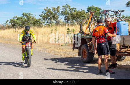 A Gibb Challenge 2018 cyclist riding past a support vehicle and trailer on the dirt Gibb River Road Kimberley WA Australia. Stock Photo