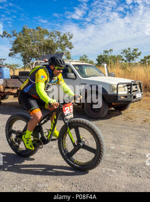 A Gibb Challenge 2018 cyclist riding past a support vehicle and trailer on the dirt Gibb River Road Kimberley WA Australia. Stock Photo