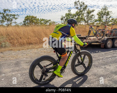 A Gibb Challenge 2018 cyclist riding past a support vehicle and trailer on the dirt Gibb River Road Kimberley WA Australia. Stock Photo