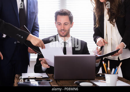 Young Businessman Looking At Document Shown By Partner Stock Photo