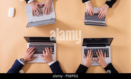 Elevated View Of Businesspeople Working On Laptop Over Beige Background Stock Photo