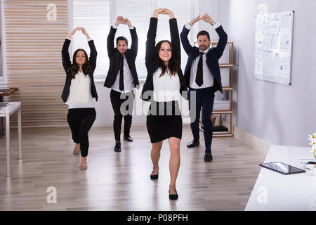 Young Businesspeople Doing Stretching Exercise At Workplace Stock Photo