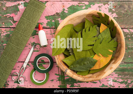Utensils for making paper flower leaves and paper flower leaves on an old wooden table Stock Photo
