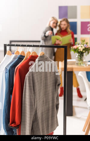 stylish dressmakers working in modern office with clothes on foreground Stock Photo